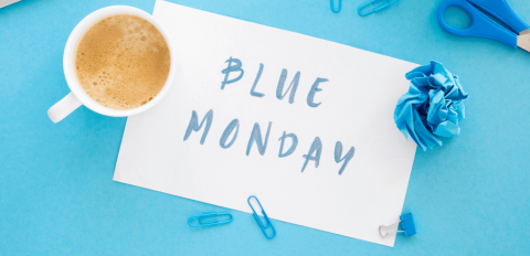 Schreibtisch in blau mit Kaffeetasse und Blatt mit Aufschrift Blue Monday